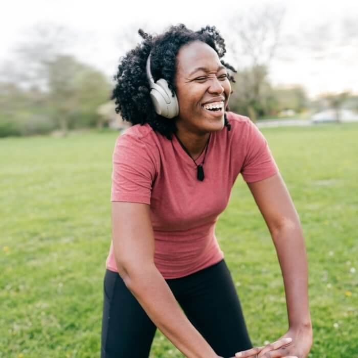 Lady wearing headphones exercising outdoors - Getting out in nature - Earthing is a principle in Biohacking