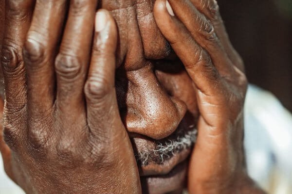 Senior black man with face in his hands looking confused which can happen from loss of insight in dementia