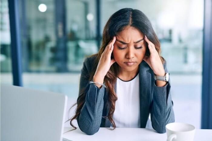 Worried looking lady holding her fingertips to sides of the head showing ffects of stress 