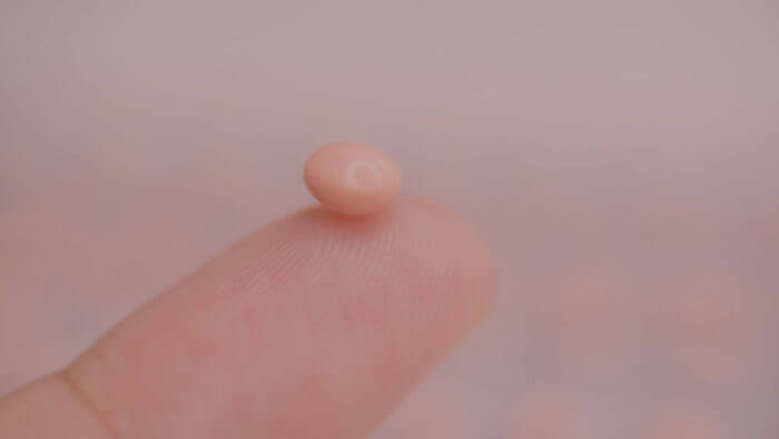 An emergency contraception pill held on a fingertip