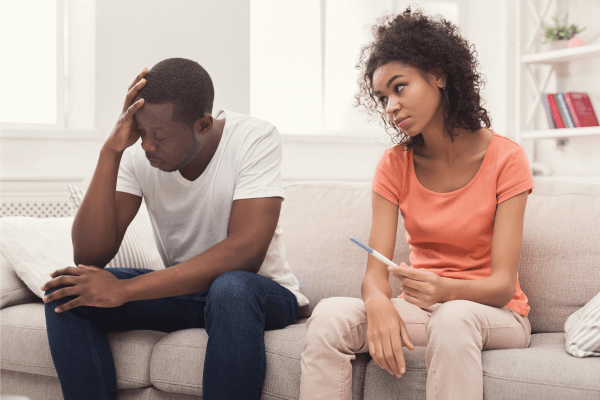 A young black couple discussing fertile window - lady in pink blouse holding a pregnancy test kit