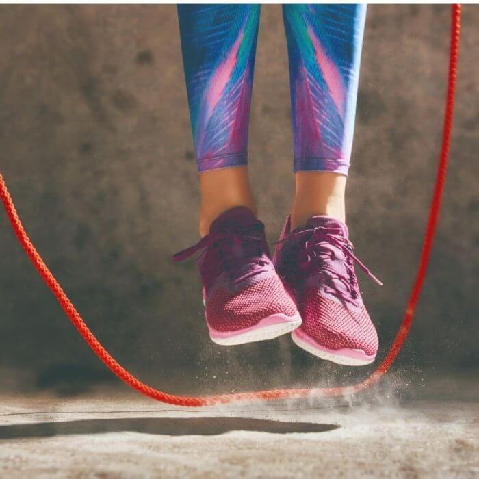 Someone in blue and purple leggings and purple trainers jumpimng rope - great cardio workout