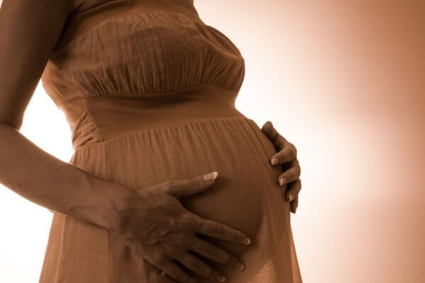 Lady in second trimester - holding her bump - awareness is important in high-risk pregnancy
