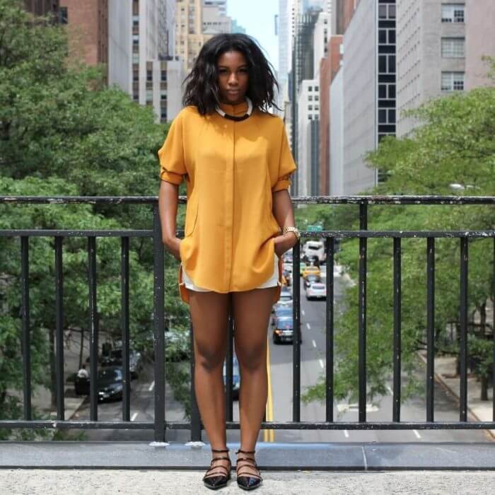 African lady dressed in casual shorts in front of a railing.
