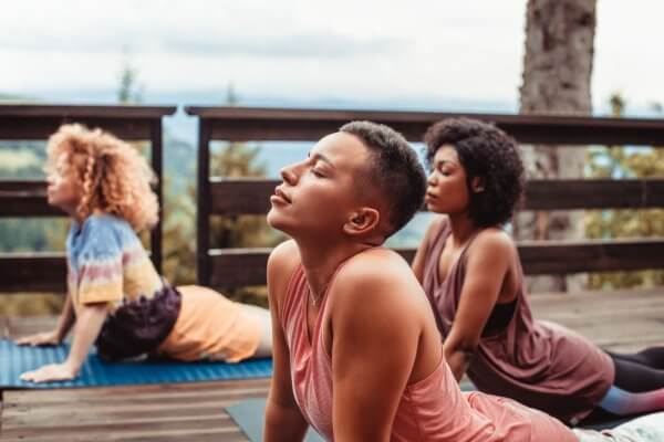 Three women in a yoga session, achieving mental wellness at a retreat