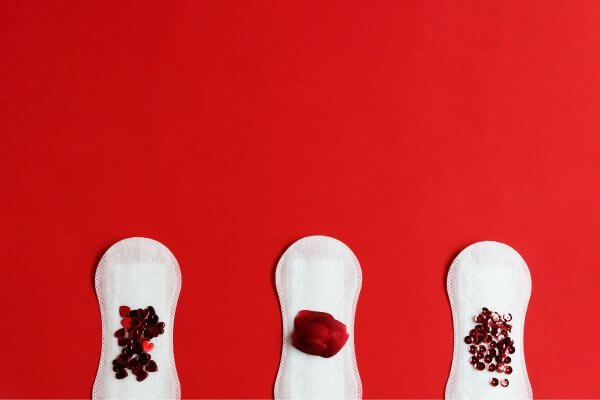 Image with 3 sanitary towels with dark red objects on the surface. Missed periods are caused by several different conditions