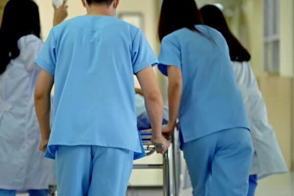 Doctors wheeling a trolley with a high-risk pregnancy mum
