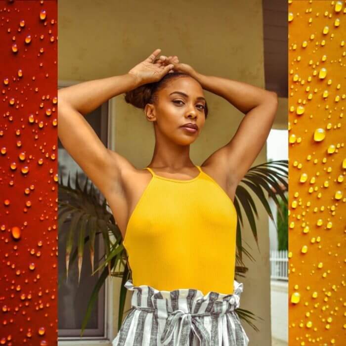 Elegant lady od africal origin standing with arms on her head exposing smooth underarms.