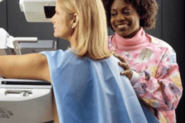 Image of a lady being assisted at a mammogram.