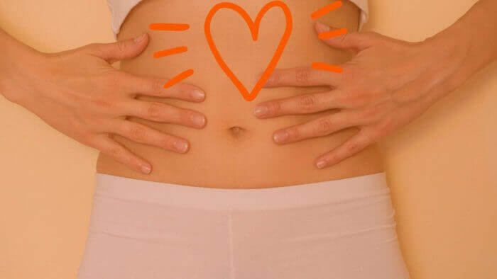 Lady holding her abdomen with a bold heart depicting the upper abdomen where stomach ulcer pain tends to occur commonly