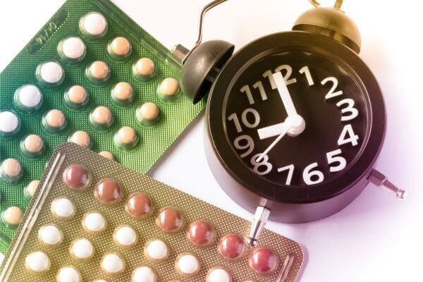alarm clock beside a packet of birth control pills