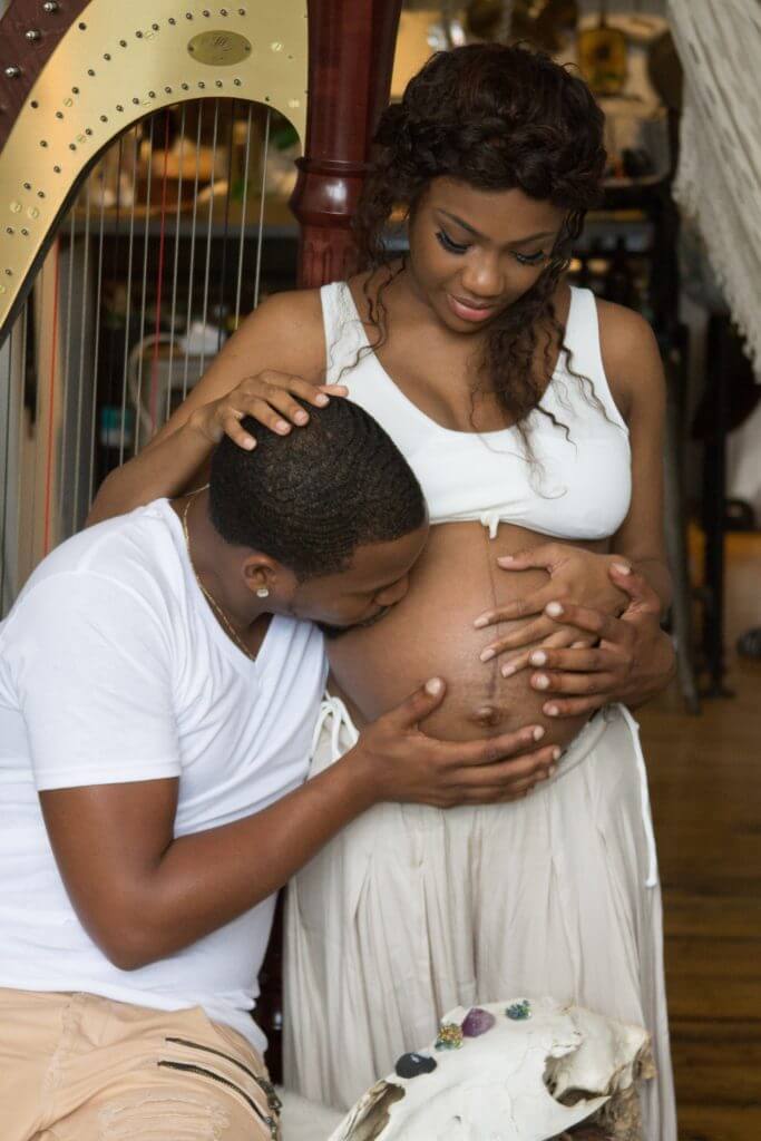 African couple embracing - man kissing lady's pregnant abdomen - Prenatal Testing in Sickle Cell Disease may help some couples.