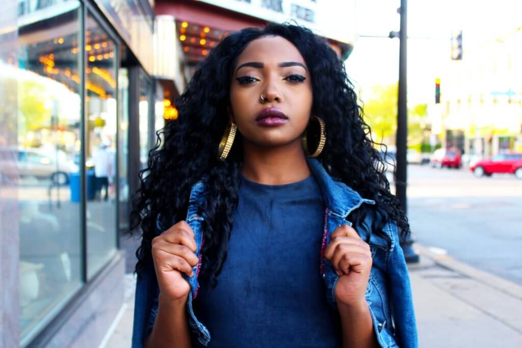 Lady of Afrocaribbean origin dressed in blue and staring boldly into the camera.