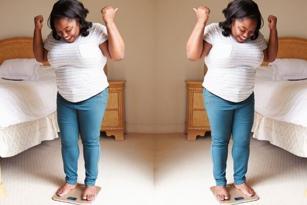 double image - happy black lady dressed in jeans standing on scales happy abut losing weight