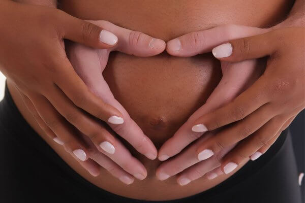 couple holding her abdomen - early pregnancy symptoms