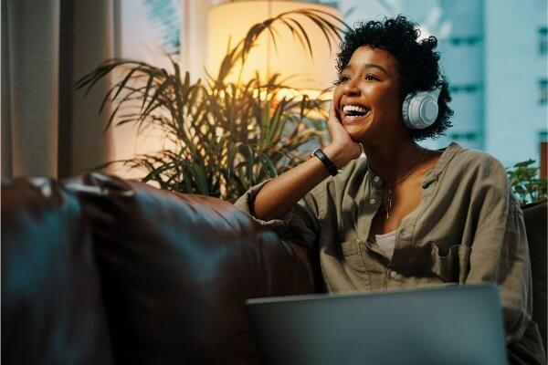 healthy change - fit looking young black lady laughing on the sofa wearing head phones