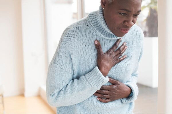 Older lady holding the middle of her chest, aware heart attack symptoms may appear differently in women 