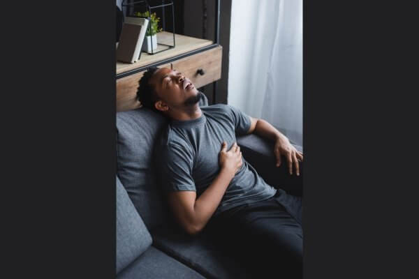 Man lying on sofa in chest pain from incoming heart attack 