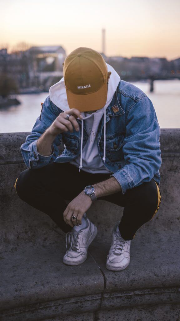 Young african man stopped with head bent over, face cap covering his face - wondering if frequent sex can reduce the risk of Prostate Cancer.