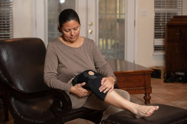 Lady sitting on the sofa massing her painful knee.