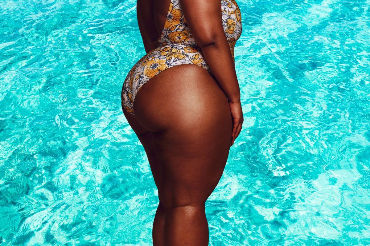 Chocolate skinned African lady in a swim suit with unwanted weight especially around the hips.